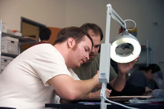 Students examining small artifacts under a light
