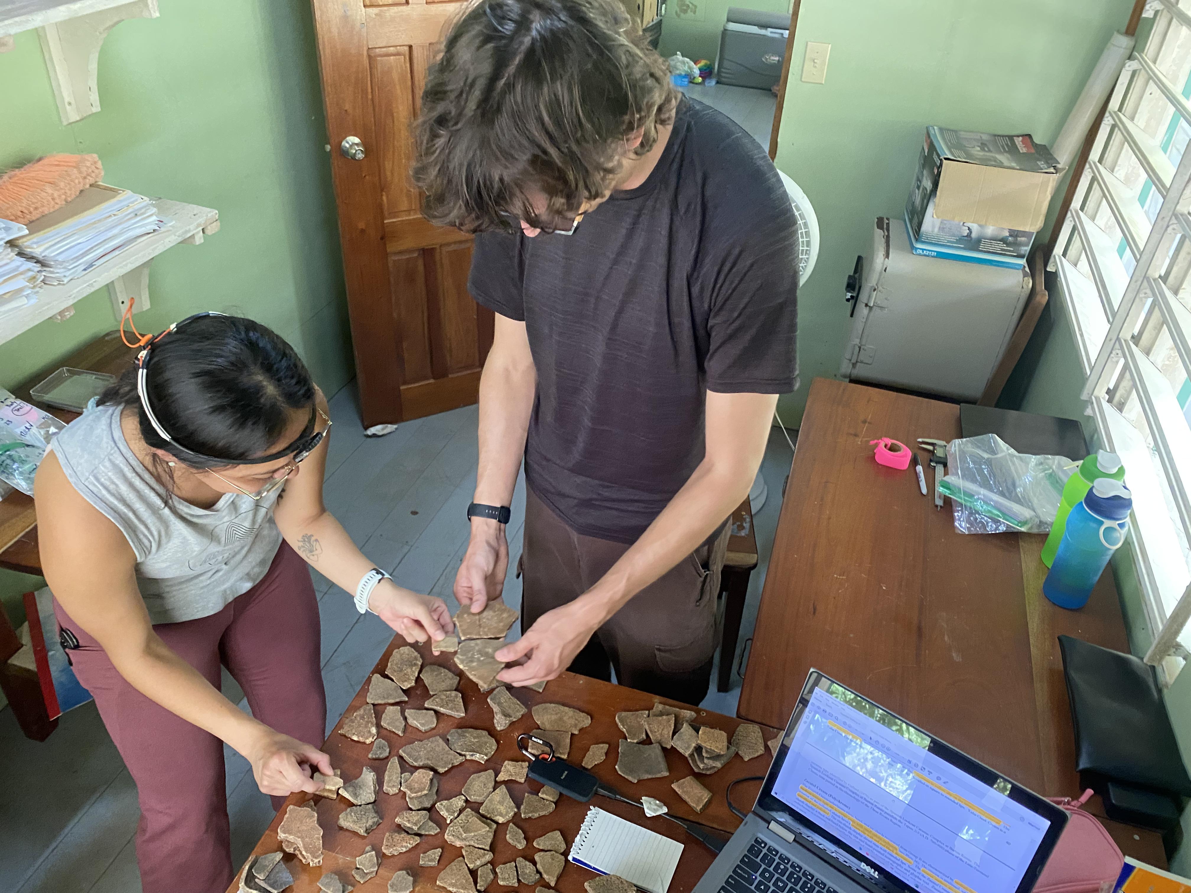 Two people looking at pieces of pottery