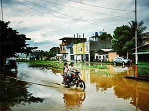 Two people on a motorcycle in a flooded street